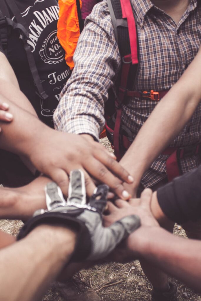 A group of diverse individuals join hands for teamwork in West Java, Indonesia.